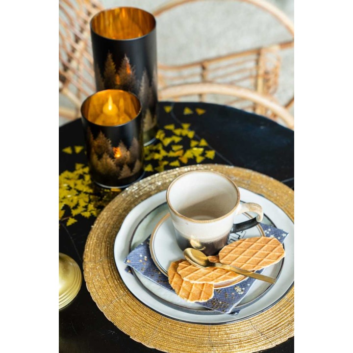Een stijlvolle tafelsetting met een gouden placemat, een mok, wafels en sfeervolle kaarsen.