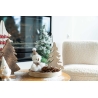 A cozy holiday scene with wooden trees, a snowy snowman, and pinecones on a warm table.