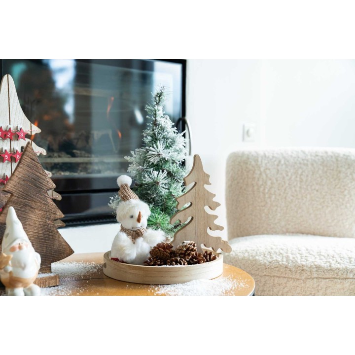 Een sfeervolle kerstdecoratie met houten bomen, een sneeuwpop en dennenappels op een tafel.