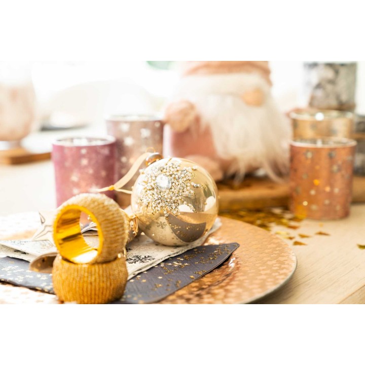 Gouden kerstbal tussen sprankelende kaarsen en feestelijke decoraties op een elegante tafel.