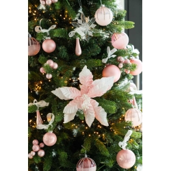 Een groene kerstboom versierd met roze ballen, een grote roze bloem en witte linten.