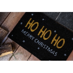 A festive black doormat with "HO HO HO" and "MERRY CHRISTMAS" in cheerful colors.