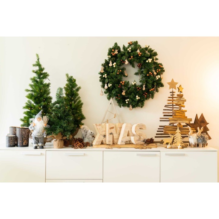Kerstdecoratie met groene bomen, een krans, houten sterren en sfeervolle accessoires op een witte...