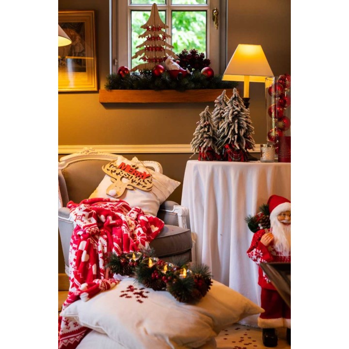 Gezellige kerstdecoratie met een stoel, kussens, lamp en versieringen in warme kleuren.