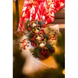 A cozy winter scene with candles surrounded by pine branches and festive decorations.