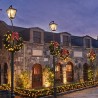 Charming stone buildings adorned with festive wreaths and warm, glowing lights under a twilight sky.