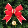 A large, vibrant red bow with gold trim adorns a lush green Christmas tree.