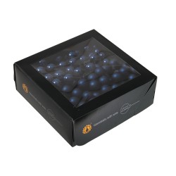 A black box with a clear lid, filled with round dark blue candies.