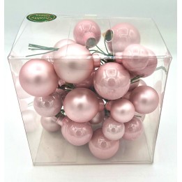 Doorzichtige doos met glanzende, roze kerstballen in verschillende maten.