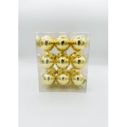 Shiny gold decorative ornaments arranged in a clear box, reflecting light beautifully.