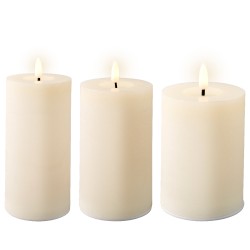 Drie witte kaarsen met een zachte gloed, rechtopstaand op een lichte achtergrond.