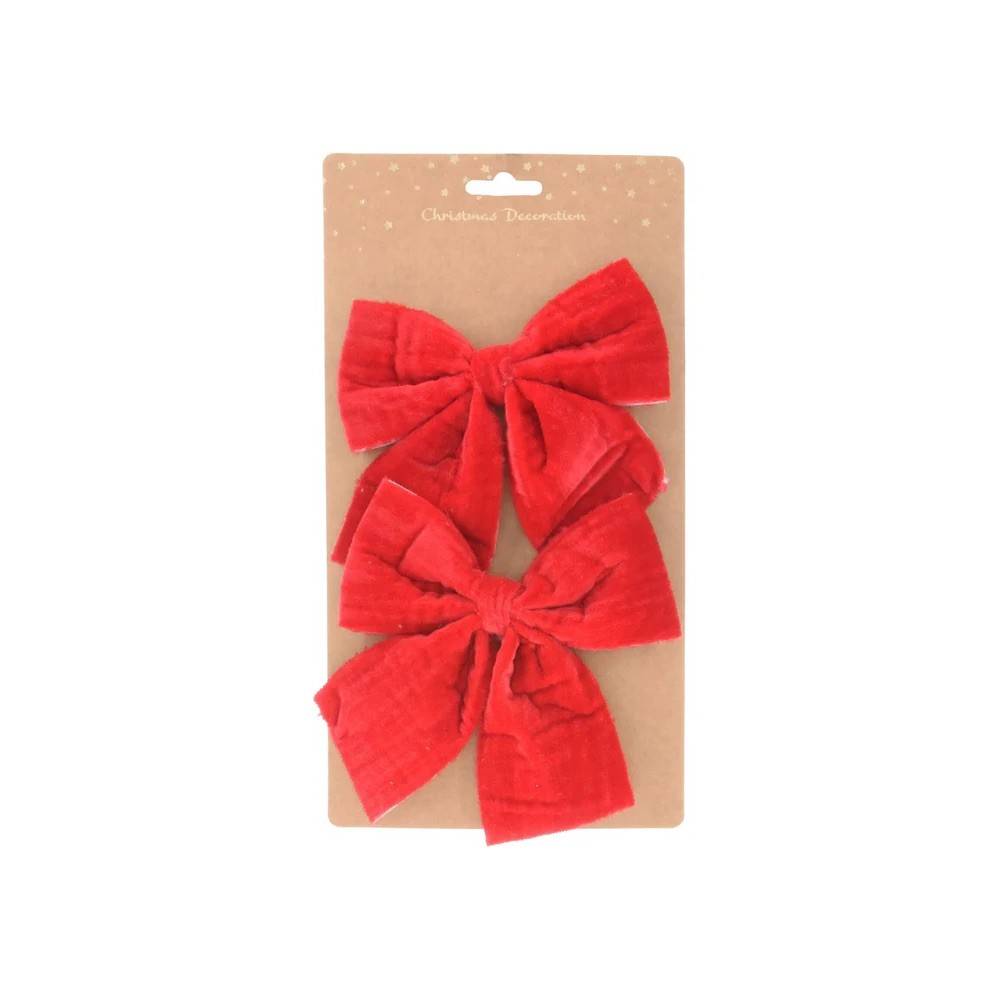 Two large, plush red velvet bows on a brown card with a subtle dot pattern.