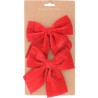 Two large, plush red velvet bows on a brown card with a subtle dot pattern.