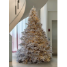 A frosted white Christmas tree adorned with warm lights, set in a modern, airy space.