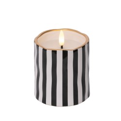 A round candle with black and white stripes and a gold rim, softly glowing from within.
