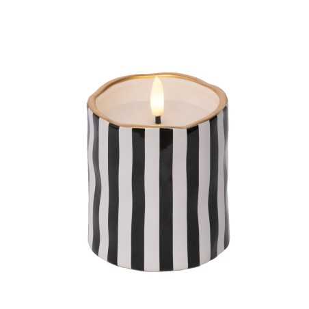 A round candle with black and white stripes and a gold rim, softly glowing from within.