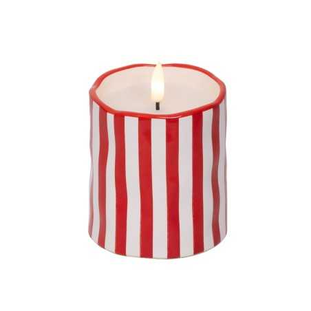 A white candle with red vertical stripes, featuring a flickering flame at the top.