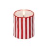 A white candle with red vertical stripes, featuring a flickering flame at the top.