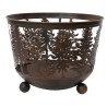 A rustic metal basket with intricate tree cutouts and rounded feet.