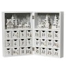 A white advent calendar with small drawers, featuring festive designs and a winter scene.
