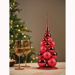 Een rode kerstboom van glanzende ballen met gouden glazen in een sfeervolle setting.