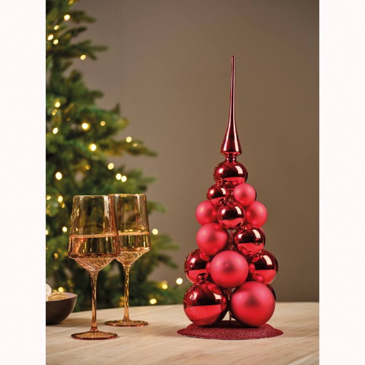Een rode kerstboom van glanzende ballen met gouden glazen in een sfeervolle setting.