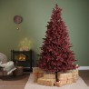 A burgundy Christmas tree stands beside wrapped gifts on a cozy, green wall backdrop.