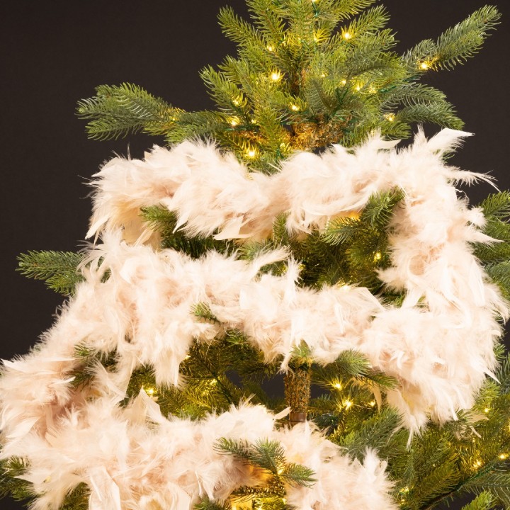 Een groene kerstboom versierd met zachte, lichte veren en twinkelende lampjes.