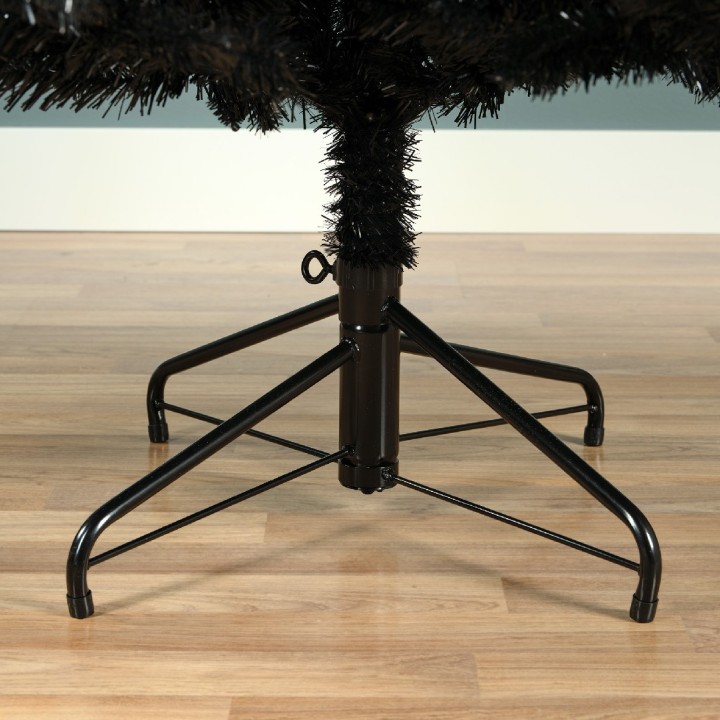 Zwarte kunstkerstboom met een metalen standaard op een houten vloer.