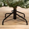 A black metal stand supports a faux Christmas tree on a light wooden floor.