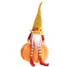 Een schattige gnoom met een lange, gouden puntmuts zittend op een oranje pompoen.