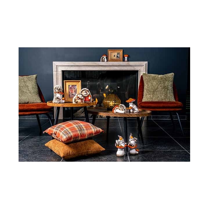 Gezellige woonkamer met fauteuils, houten tafels, kussens en schattige decoraties bij een haard.