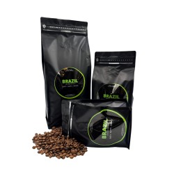 Three black coffee bags of varying sizes, surrounded by scattered coffee beans.