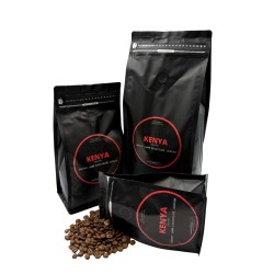 Drie zwarte koffiepakketten met rode labels, omringd door gemalen koffiebonen.