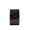 A sleek black coffee bag with bold red and white text, featuring earthy flavor notes.