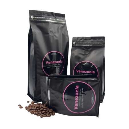 Drie zwarte koffiezakken met roze labels, omringd door losse koffiebonen.