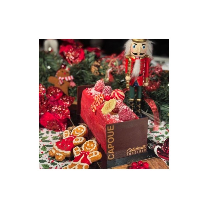 Kersttaart met rood glazuur, versierd met snoep, naast een notenkraker en gingerbreadkoekjes.