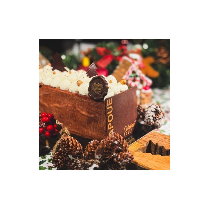 Een feestelijke chocoladetaart met crème, versierd met chocolade en gouden parels, omringd door ...