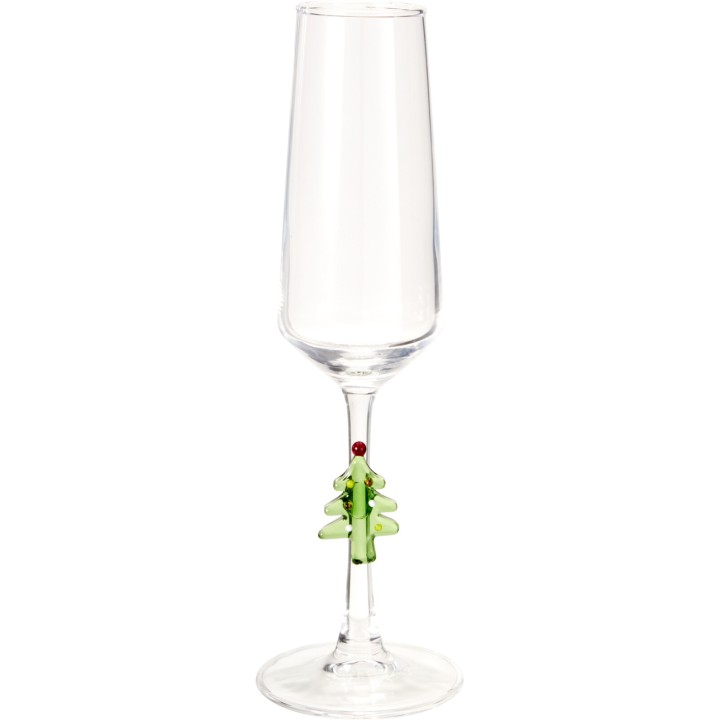 A clear champagne flute with a decorative green Christmas tree charm on the stem.