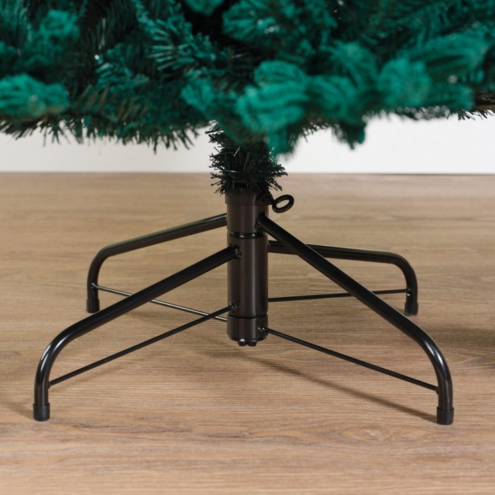 Groene kunstkerstboom met een metalen standaard op een houten vloer.