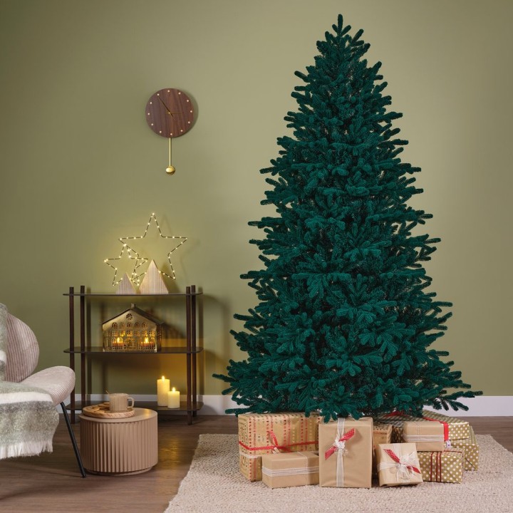 Groene kerstboom met cadeaus in een warme, sfeervolle kamer met een neutrale muur.
