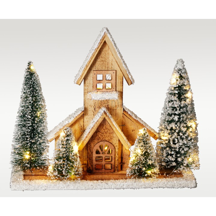 Houten huisje omringd door groene dennen, versierd met sneeuw en warme lichtjes.