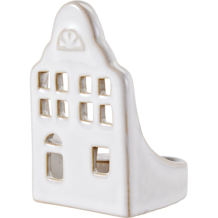 A white ceramic ring holder shaped like a quaint house with window cutouts.