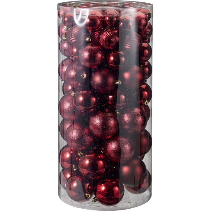 A clear cylinder filled with shiny red Christmas ornaments, varying in size and texture.