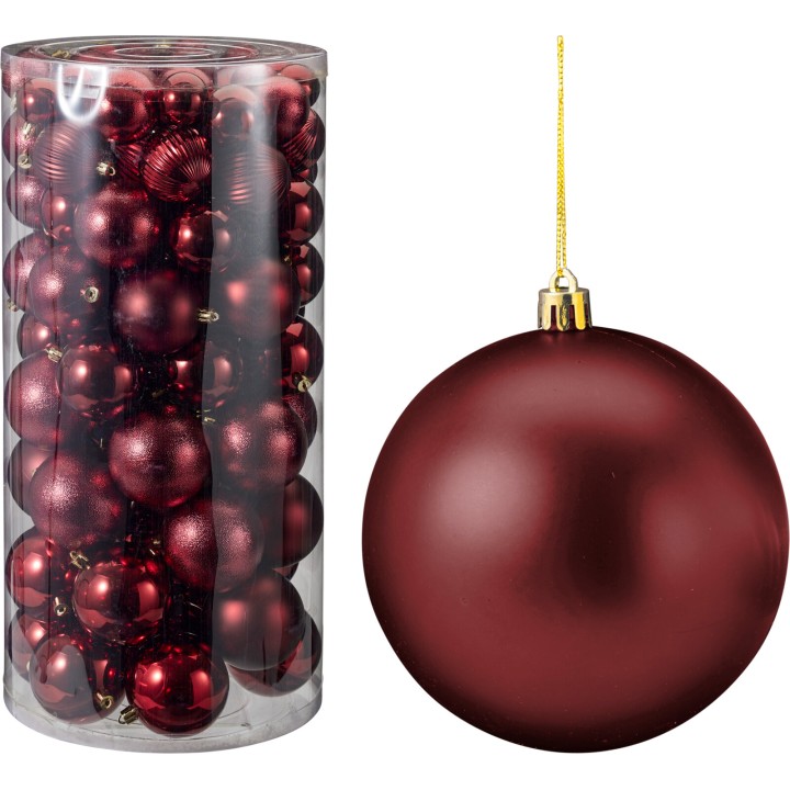 A clear container filled with shiny red ornaments beside a large red bauble.