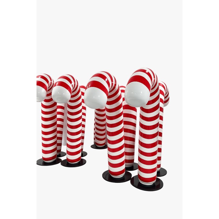 Zes gestreepte figuren met een witte bolle bovenkant staan op zwarte bases, in rood-witte strepen.