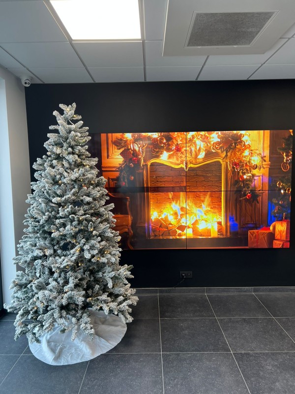 Besneeuwde kerstboom bij een open haard